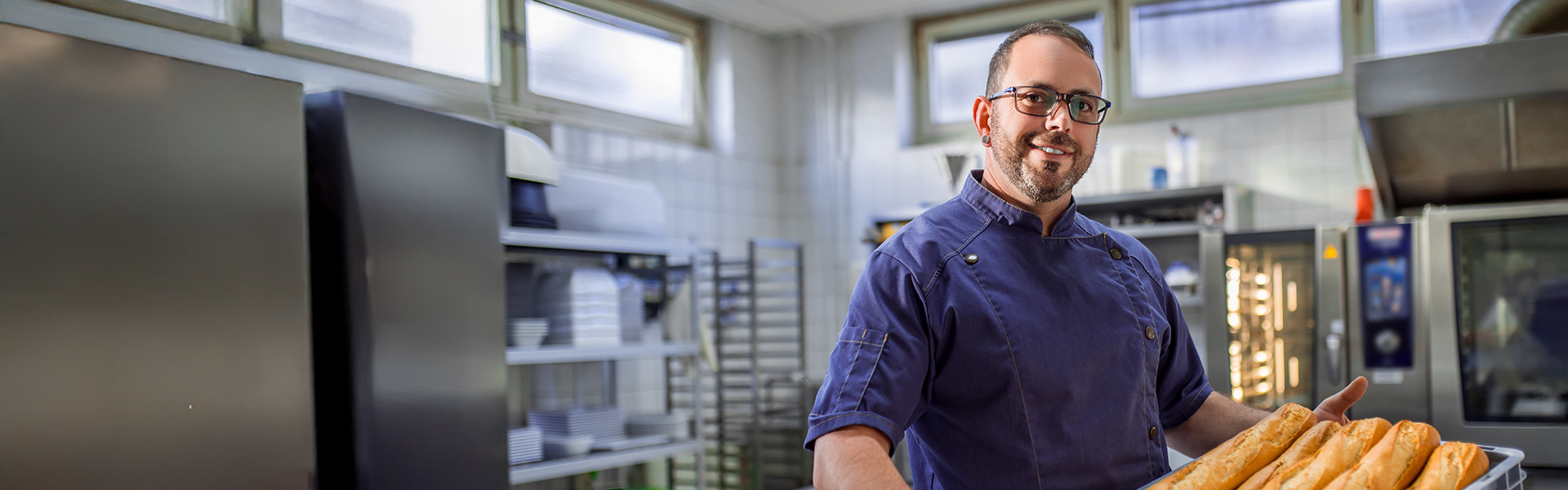 Gastronomie-Mitarbeiter in einer Küche trägt einen Brot voller Baguettes