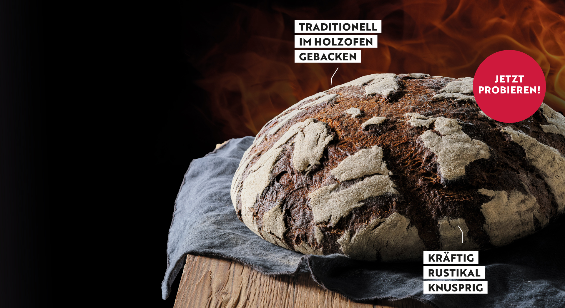Ein Fränkisches Holzofenbrot liegt auf einem mit einem blauen Leinentuch bedecktem Holzuntergrund
